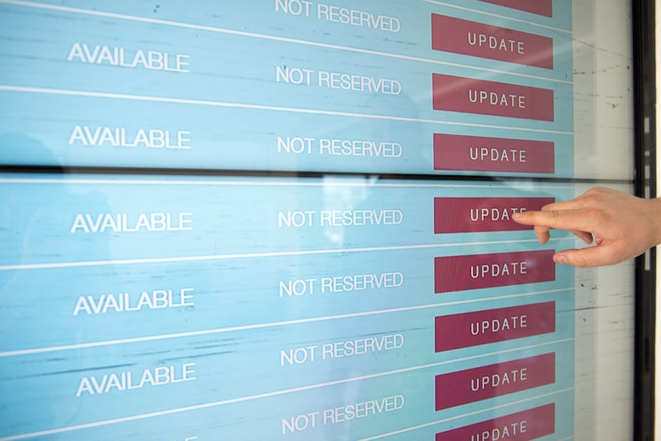 A person is pointing at a digital screen displaying appointment schedules related to garden maintenance services in Islington, with rows labeled 'AVAILABLE' and 'NOT RESERVED' alongside red 'UPDATE' b